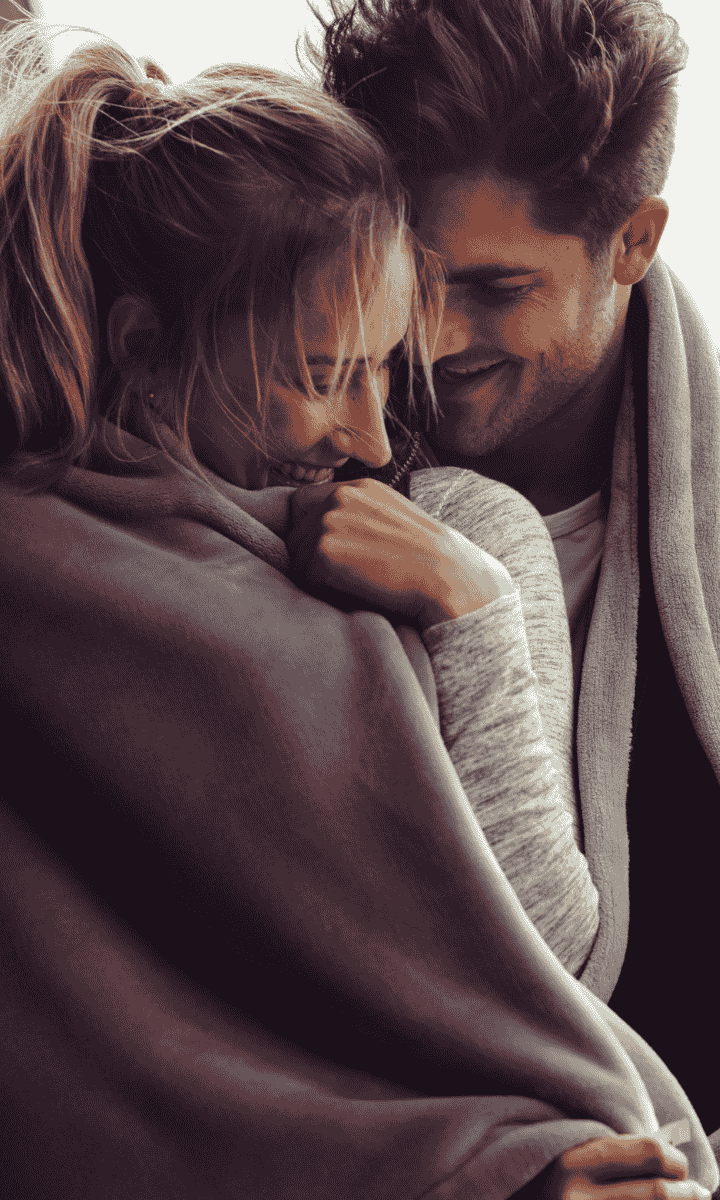 Couple snuggled up, wrapped in blanket enjoying each others company.